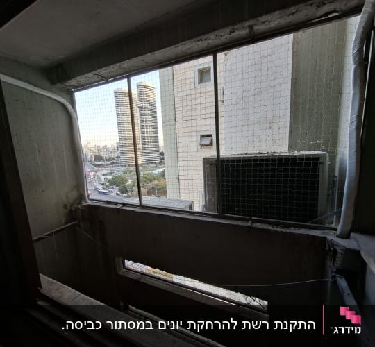 רשת יונים מותקנת בחלון בניין גבוה
